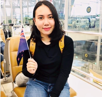 นักเรียนหญิงถือธงชาตินิวซีแลนด์บนเครื่องบินระหว่างเดินทางไปเรียนต่อ